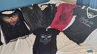 Six Harley Davidson ladies shirts laid out showing front sides and designs.