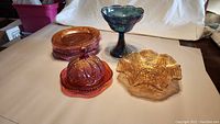 Overview of all carnival glass pieces: blue candy dish, amber tea plates, covered butter dish, serving dish