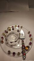 Clear glass serving plate with embedded amber and deep red glass accents and placed bowl and utensil on top.