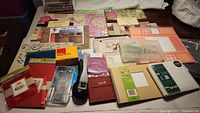Full view of various scrapbooking supplies including albums, paper pads, tool kits, and embellishments arranged on a table.