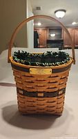 Front view of the Longaberger Glad Tidings basket showing woven wood body, wooden handle, and green/white striped fabric liner.