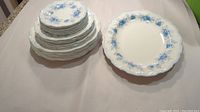 Stack of various sized plates and two serving dishes shown on flat surface.