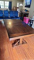 Full view of the closed dining table showing dark wood finish with paneled top and trestle base.