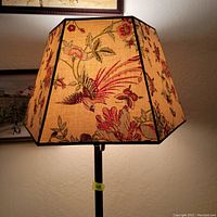 Close-up of the hexagonal floral fabric lampshade with bird and leaf patterns illuminated.