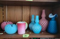 Group of pink, blue, and yellow ruffle rimmed bowls and one pink tumbler