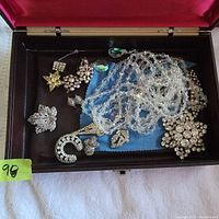 Box containing a collection of vintage beaded and crystal jewelry including necklaces, brooches, earrings, and pins.