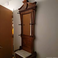 Front view of wooden hall tree showing crown top, mirror and hooks