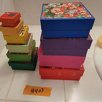 Photograph of ten Japanese nesting boxes stacked in two towers showing various sizes and colorful floral lids.