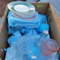 Box containing assorted Depression glass including clear and pink glass plates, tumblers, a salt shaker, and a mug.