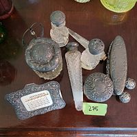 Photo of a vintage vanity lot with intricately cut glass jars and containers, silvered lids, two salt/pepper shakers, long slender perfume bottle, an oval silvered case, and a silvered date calendar frame showing September.