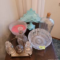 Overview of seven vintage glass and metal serving items on a wooden table, showing various views and details.