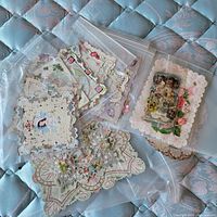 Photo showing multiple vintage valentines in plastic sleeves on a quilted surface, highlighting intricate lace and floral designs.