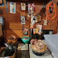 Photo showing various packaged hand tools and accessories hung on pegboard with bowls containing screws and decorative trivets on table