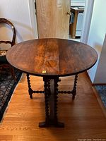 Front view of barley twist round wooden table with drop leaves extended, showing the gate legs and barley twist design.
