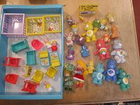 Overview of miniature dollhouse furniture and Care Bears figures in lot