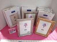 Overview of the lot showing 6 boxed photo frames by Burnes, two frames displayed in front (silver and gold leaf Windsor style) and 4 boxed in the back.