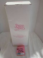 Tall white Precious Moments box with pink logo and text.