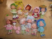 Wide view of all 10 dolls in lot arranged on wooden surface