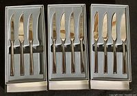 Three boxes containing eleven serrated knives arranged neatly in foam inserts.