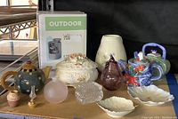 Overview of the various collectible and decorative items displayed together on a shelf, including teapots, trinket boxes, and glass ornaments.