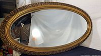 Front view of large oval wall mirror with ornate vine decorated frame showing the mirror surface and frame details