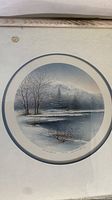Photo showing the framed lithograph "Quiet Shores" with visible weathering on the frame and the image of a winter landscape.