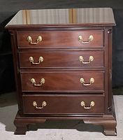 Front view showing four drawers with brass handles and the overall shape and style of the chest.