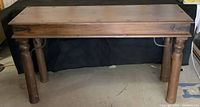Front view of the whole wooden console table showing top, legs, and metal supports.