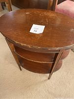 Top down view showing the oval shape and water damage with scratches across the wooden surface of the accent table.