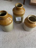 Set of three two-tone antique English crocks arranged on carpet showing size and shape variations