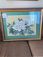 Full view of framed embroidered flower artwork showing white flowers on gold background with green leaves.
