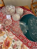 Top view of crystal custard bowl, 6 bowls and 3 glass serving plates displayed on patterned cloth.