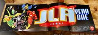 Photo of the full opened JLA Year One promotional banner showing the title and characters.
