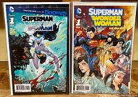 Photo showing front covers of two comic books: Superman/Wonder Woman Annual #1 and Superman/Wonder Woman #1, displaying cover art and titles clearly.