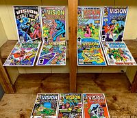 Overview photo showing eleven issues of Vision and the Scarlet Witch comics arranged on wooden shelves, front covers visible.