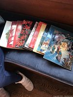 Top view of eleven Ideals Christmas magazines arranged side by side, showcasing varied vintage covers with holiday illustrations and colors.