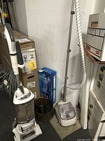 Full view of Shark vacuum, clothing steamer, copper pot and boxed Christmas tree in the corner