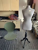 Green molded side chair and white fabric dress form on tripod stand in office setting