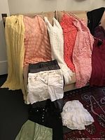 Photo of assorted women's dresses and skirts in various colors on a couch, showing styles and fabrics