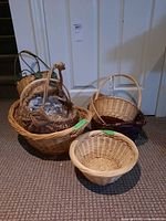 Seven wicker baskets of different sizes and shapes placed on carpet in front of a door.