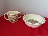 Photo showing the Bunnykins bowl and two-handled cup together on a red surface with white background, highlighting their size and shape
