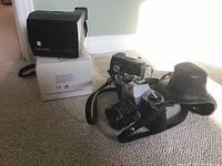 Polaroid 635 CL instant camera and Honeywell Pentax 35mm film camera with leather case on carpet floor.