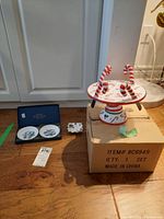 Photo showing the two small Royal Worcester dishes in box, James Kent dish, and candy cane themed pedestal cheese plate with spreaders on a wooden floor.