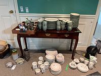 Front view of the wood console table with decorative metal hardware, drawers visible, and various items on and below it (items not included).