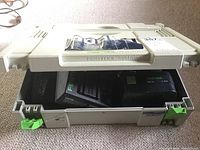 Beige Festool Systainer carrying case partially open showing some contents inside.