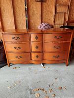 Front view of dresser showing serpentine drawer layout and decorative metal pulls