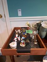 Photo showing small assorted ceramic and porcelain animal figurines on a wooden tray with dark inlay and handles.