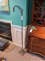 Full view of the metal floor lamp standing near fireplace and furniture, showing its height and curved top arm.