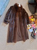 Full length brown mink fur coat laid flat showing overall length and texture.
