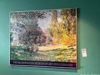 Full front view of framed art print hung on teal wall, showing colorful impressionistic landscape and museum text border.